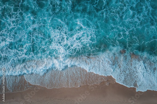 Fototapeta Naklejka Na Ścianę i Meble -  Aerial view of sea waves crashing on the shore, abstract nature landscape with light and water elements