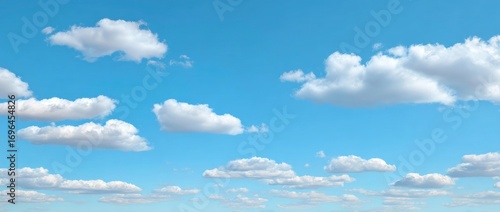 A calming image featuring a bright blue sky dotted with fluffy, white clouds of varying sizes, creating a peaceful and expansive scene