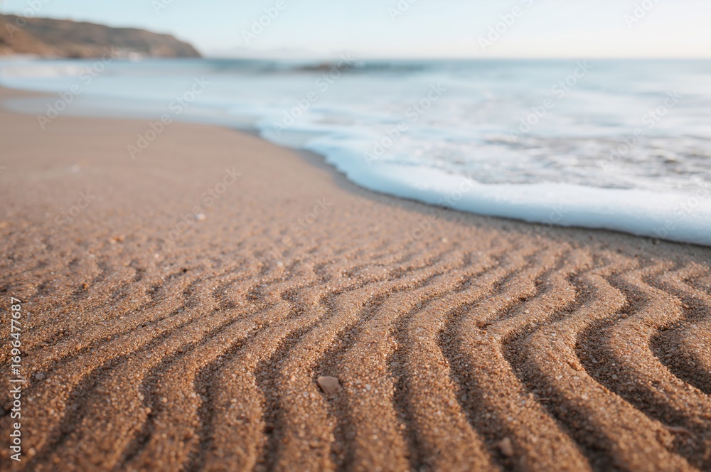 Fototapeta premium Sea-formed sand patterns on a tranquil shoreline, showcasing nature's artistry.