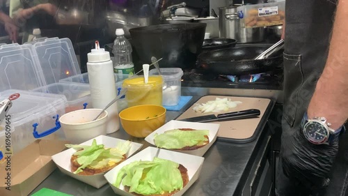 A chef prepares burgers in a cafe kitchen.
