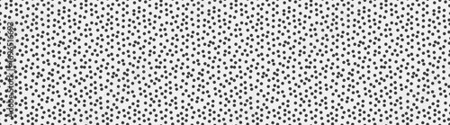 Abstract monochrome dotted pattern.  A seamless texture of small, randomly dispersed black dots on a white background.