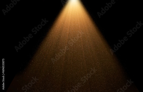 Golden spotlight is illuminating dust particles floating in dark room