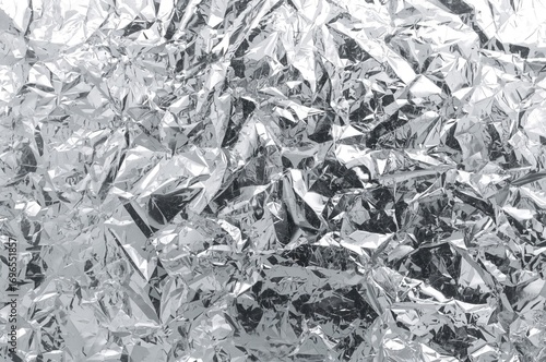 Crinkled aluminum foil with blurred texture, metallic surface background, silver distressed design, patterned material, shiny chrome-like sheet, grey tone, space for text, out of focus