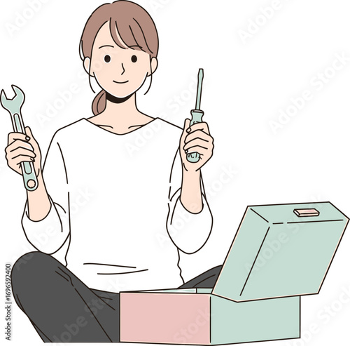 Capable young woman smiling with a wrench and screwdriver in hand, sitting in front of her toolbox, ready for a DIY home improvement project