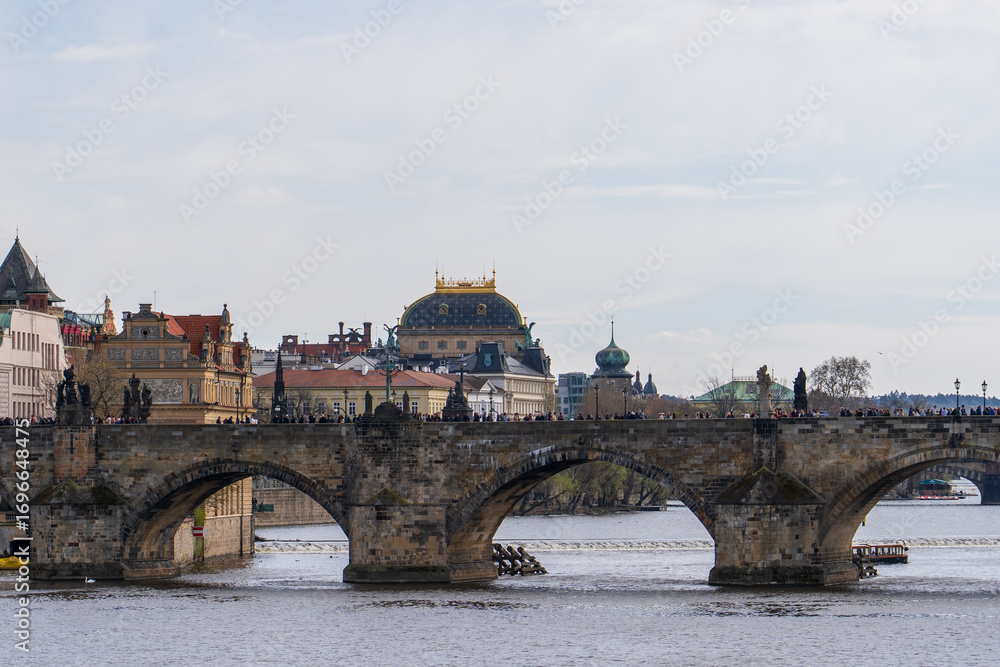 Fototapeta premium Prague, Czech Republic - April 5, 2025: View of the Charles Bridge and the Vltava River with ships passing by