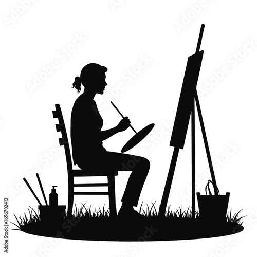 Silhouette of female artist painting outdoors with bucket Keywords: artist, painting, easel