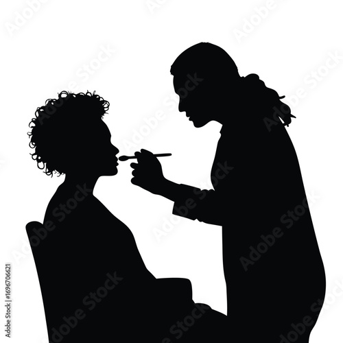 Silhouette of makeup artist applying makeup to client