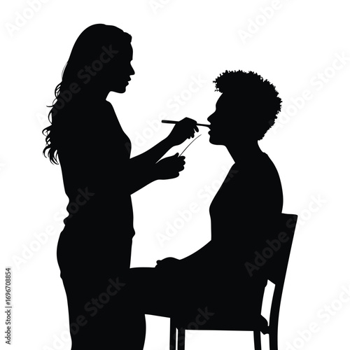 Silhouette of makeup artist applying makeup to seated client