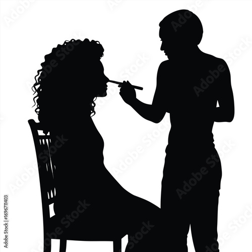 Silhouette of makeup artist applying makeup to woman with curly hair