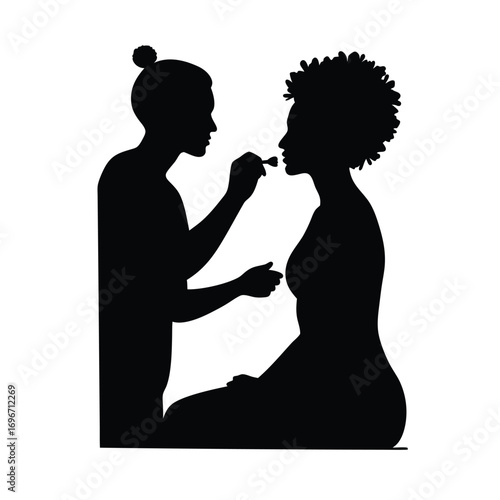 Silhouette of makeup artist with bun applying makeup to woman Keywords: silhouette, makeup