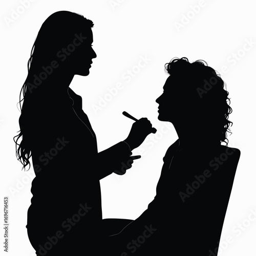 Silhouette of woman applying makeup to client in chair
