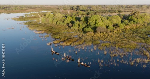 High aerial panning. Tourists enjoying a Mokoro safari on the waterways of the Okavango Delta  