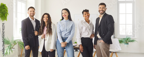 Vászonkép Group of smiling diverse business professionals standing together in modern office space