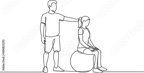 Fitness trainer guiding woman during exercise on a stability ball