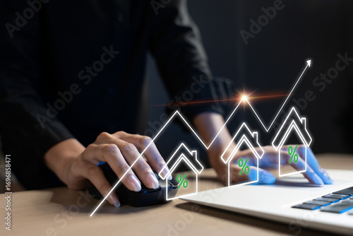 Real estate investor analyzing property market trends on laptop, with rising house icons and interest rate symbols representing investment growth, mortgage rates, and housing market analytics.