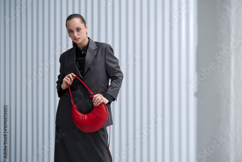 Girl model in stylish clothes with bag posing in studio