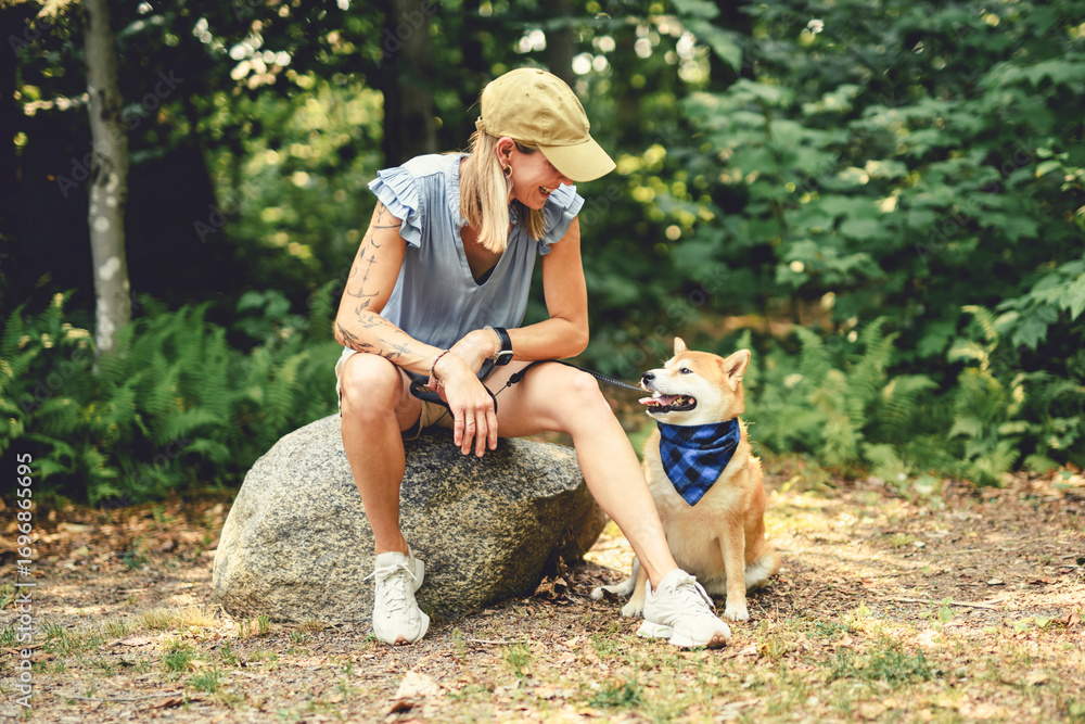 Fototapeta premium Happy woman with her Shiba Inu dog in the forest on summer season