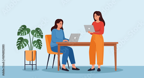 Two women working on laptops at a desk with a potted monstera plant.