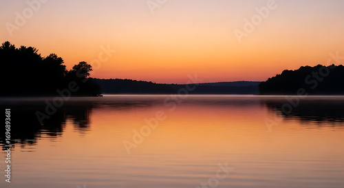 Wallpaper Mural Calm lake reflecting the warm colors of the sunset with trees silhouetted against the sky line ai generated Torontodigital.ca