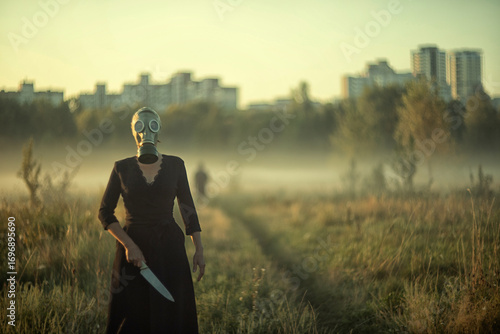 Fototapeta A mysterious masked woman holding knife in foggy field