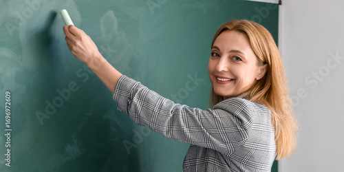 Mature teacher writing on c...