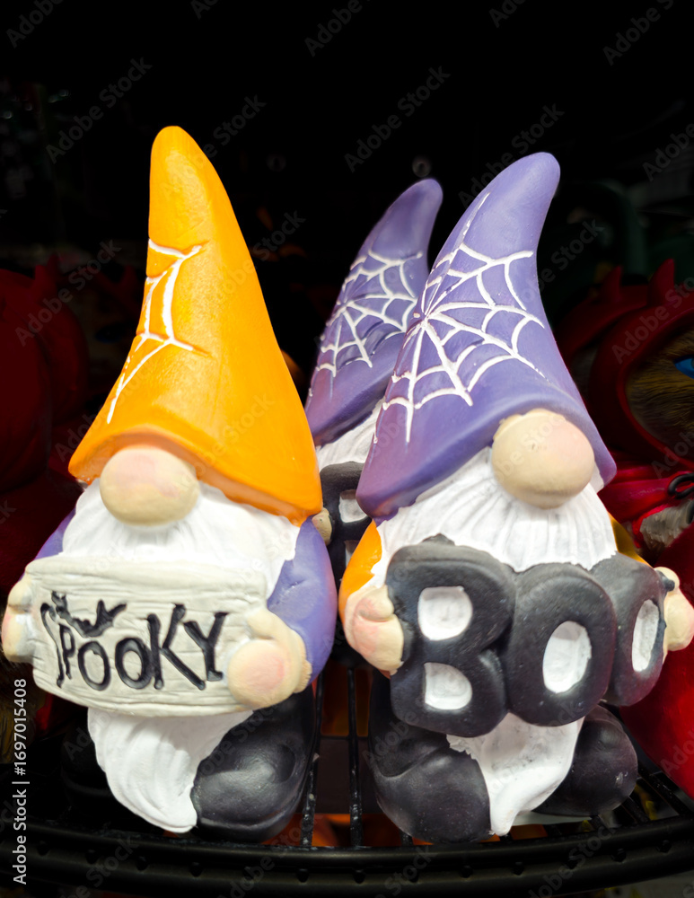 Ceramic gnome figurines for Halloween with thematic signs, standing on a counter in a store