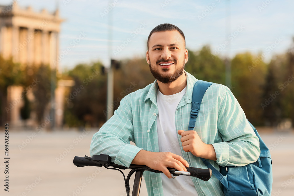 Obraz premium Handsome young man on electric scooter at city street