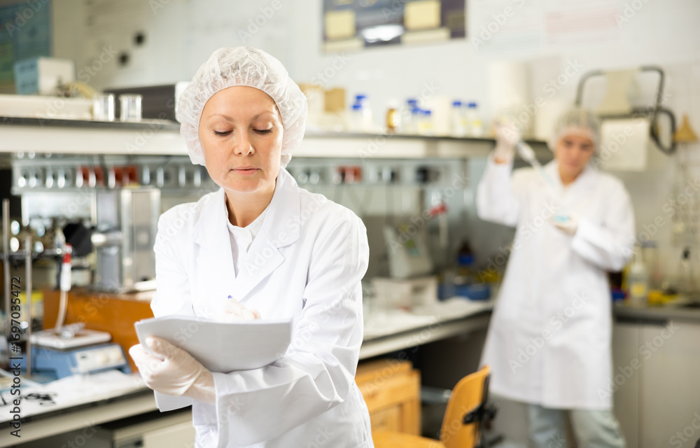 Obraz premium Confident woman technical expert taking notes while conducting experiment in science lab