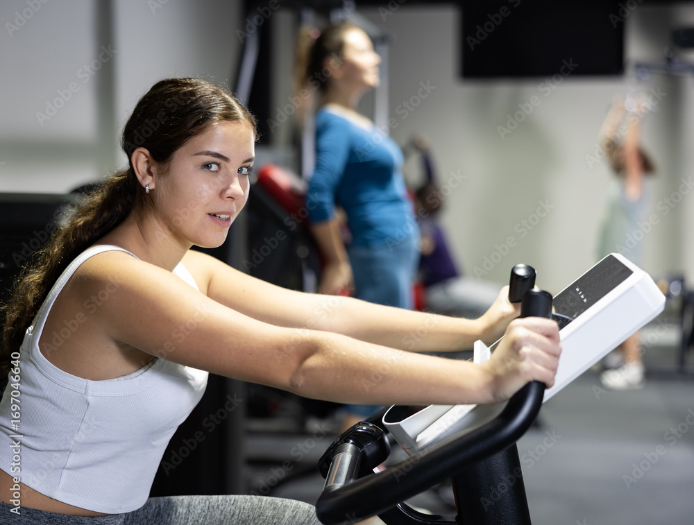 Obraz premium Caucasian woman training on exercise bike in gym