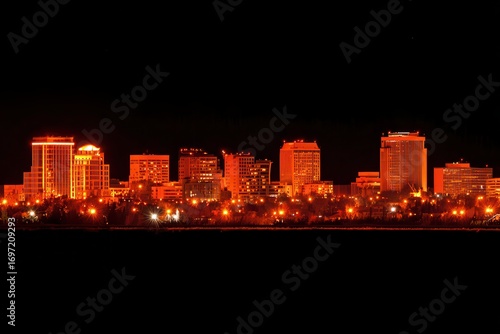 A stunning city skyline illuminated in orange and black at night, creating a beautiful contrast of colors. The city lights shining brightly against the dark sky give a vibrant and energetic feel.