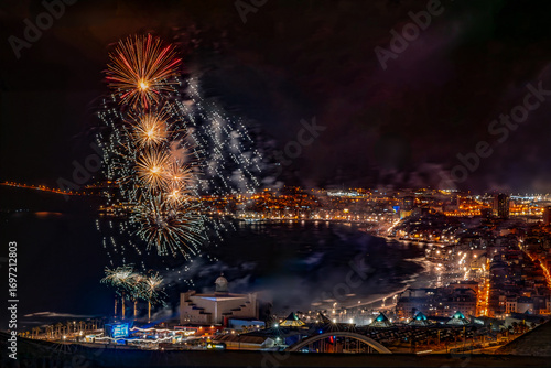 Colorful fireworks exploding over las palmas de gran canaria city by the atlantic ocean at night