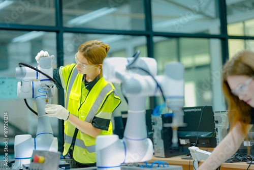 Two female students in a technology class work with robotic arms. They are learning about programming and automation, preparing for careers in engineering and advanced manufacturing.