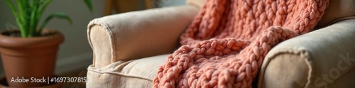 Cozy and warm knitted blanket draped over a plush armchair, perfect for a restful nap Soft textures and inviting colors create a serene atmosphere of comfort and relaxation , home, autumn, colors