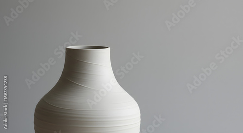 Ceramic vase with textured spirals and rounded form on gray backdrop, softly lit in studio
