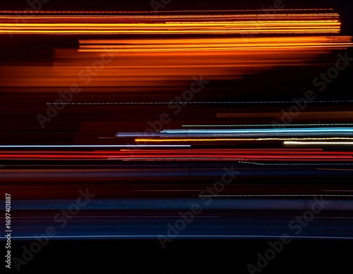 Abstract long exposure photograph of colorful light trails from city traffic streaking across a dark background.