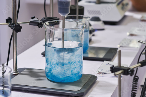 Fotografie Laboratory equipment mixing clear blue liquid in a beaker on a hot plate