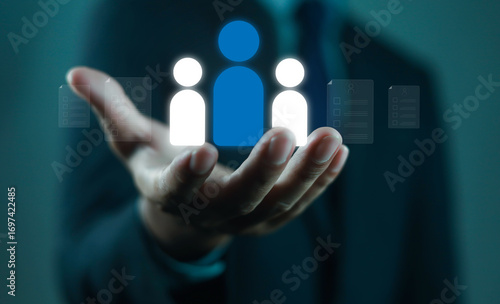 Businessman holding digital human resource icon with employee profiles, symbolizing recruitment, HR management, staff selection, corporate workforce strategy, and human capital development in modern.