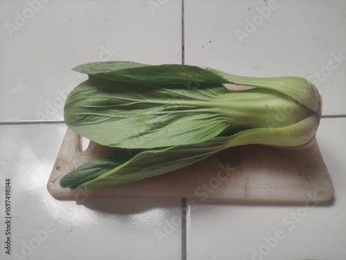 Fresh bok choy placed on wooden cutting board, close-up photo of healthy Asian leafy green vegetable