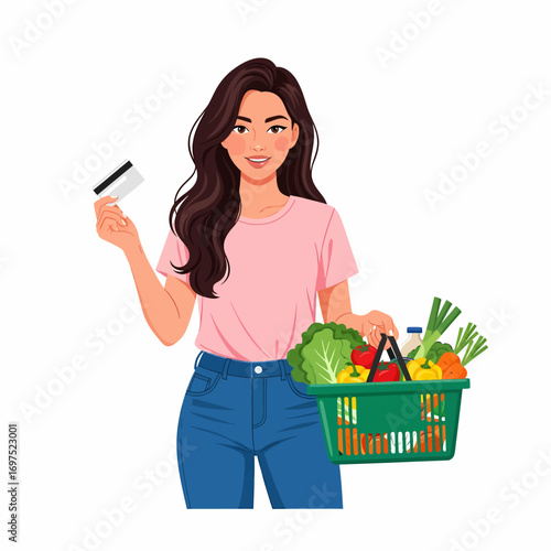 A young woman holding a credit card and a shopping basket full of fresh groceries, ready to pay.