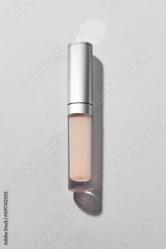 Sleek transparent cosmetic tube with metallic cap on grey background with shadow , ideal for lip gloss, concealer, or serum. Abstract beauty product advertising or branding.