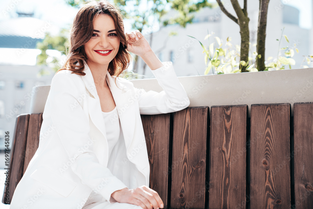 Fototapeta premium Young beautiful brunette woman wearing nice trendy white suit jacket. Sexy smiling model posing in the street at sunny day. Fashionable female outdoors. Cheerful and happy. Evening makeup, red lips