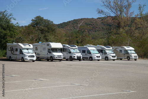 Six camping cars alignés sur une grande place