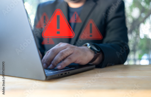 Businessman using laptop with spam virus with warning to alert internet security and data breach or hacker or spyware. Compromised information internet.