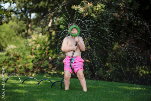 Fun Loving Child Plays with Water Hose in Backyard