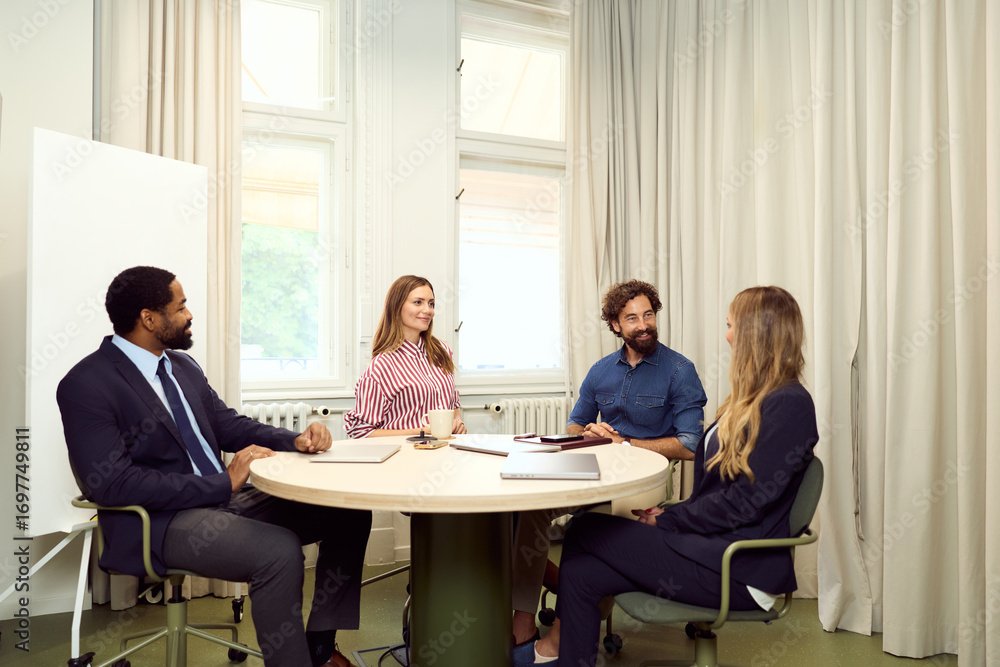 Obraz premium Colleagues Having a Business Meeting Around a Round Table in an Office Setting