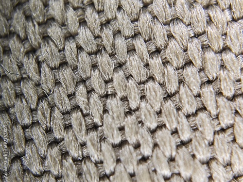 A detailed macro close-up of a woven metal fabric used for heat resistance. The intricate, interlocking pattern creates a unique abstract texture, perfect for industrial, technology