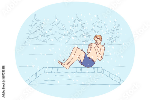 Man hardens himself by swimming in cold winter pond, jumping into icy water during snowfall. Guy hardens in forest bath to improve immunity and get ideal health helping to avoid colds and flu