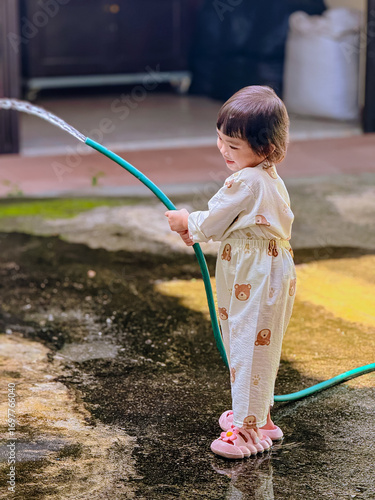 Girl outdoor activity. Children playing water outdoor with happiness in pajamas on sunny day 