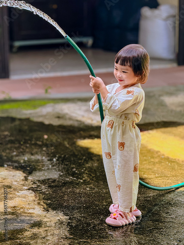 Girl outdoor activity. Children playing water outdoor with happiness in pajamas on sunny day 