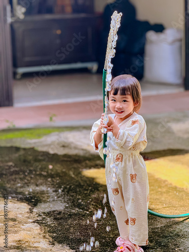 Girl outdoor activity. Children playing water outdoor with happiness in pajamas on sunny day 